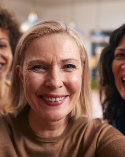 Group Of Mature Female Friends Posing For Selfie On Mobile Phone At Home